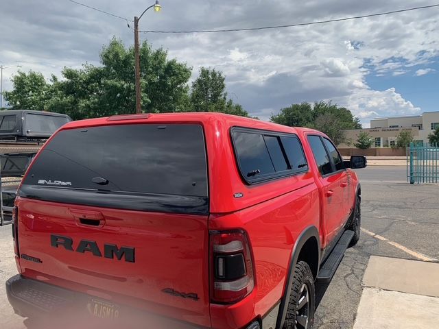 White pickup truck driving in a field, kicking up dust.
