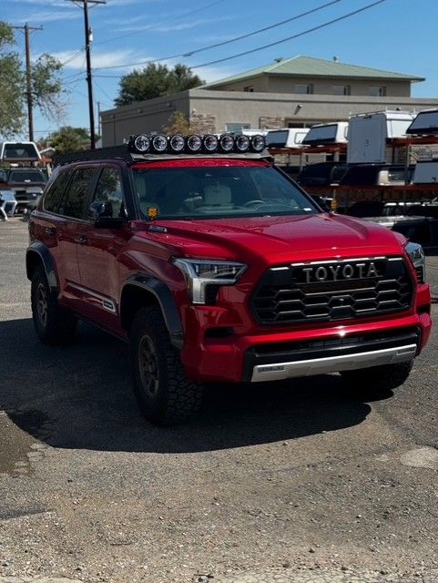 Lineup of blue, white, and black pickup trucks parked in a row on pavement; outdoor setting.