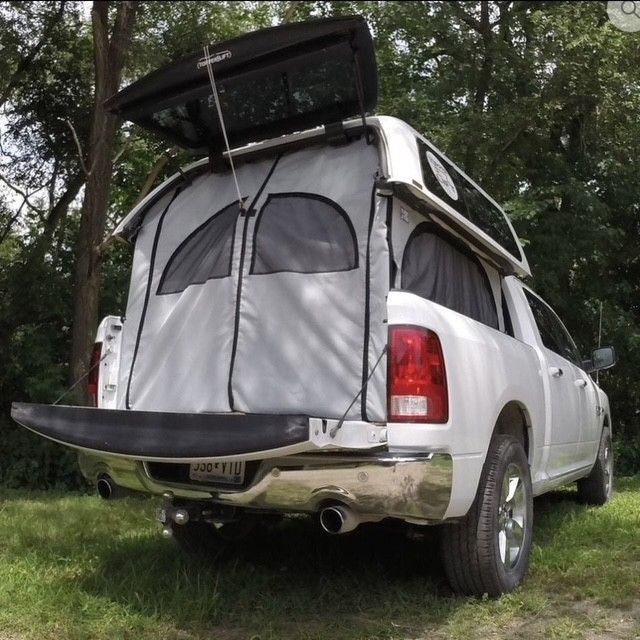 Black pickup truck driving on an empty highway, with mountains and trees in the background.