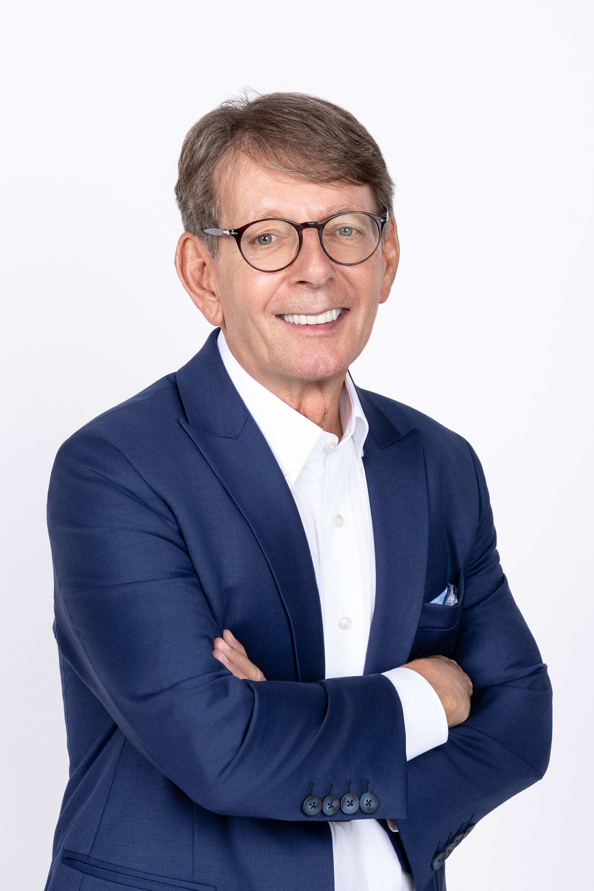 A man in a suit and glasses is smiling for the camera.