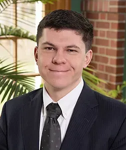 A young man in a suit and tie is smiling for the camera.