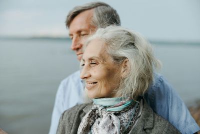 A man and a woman are sitting on the beach looking at the water.