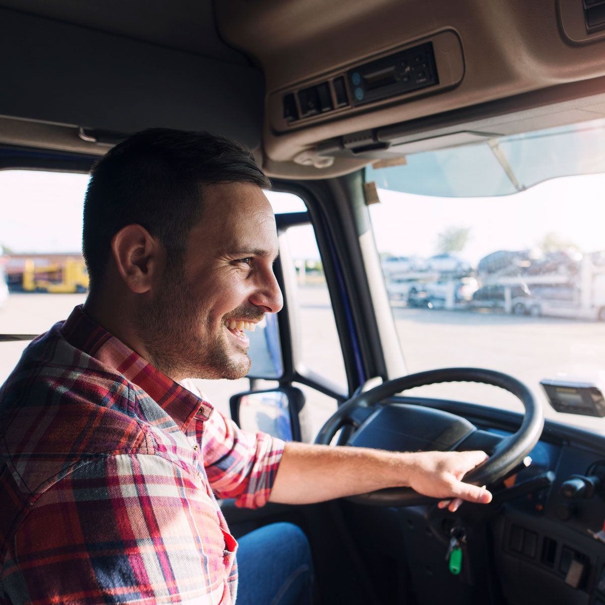 A man in a plaid shirt is driving a truck.