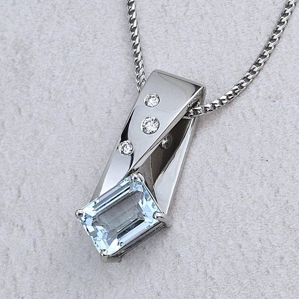 An unusual platinum pendant with an emerald-cut Aquamarine and thee diamonds
