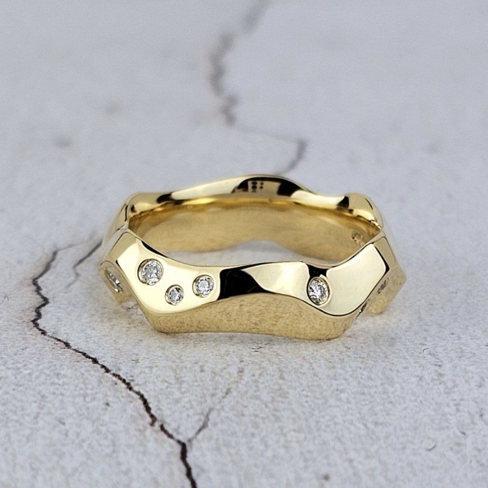 carved gold wedding band with apex profile and scattered diamonds