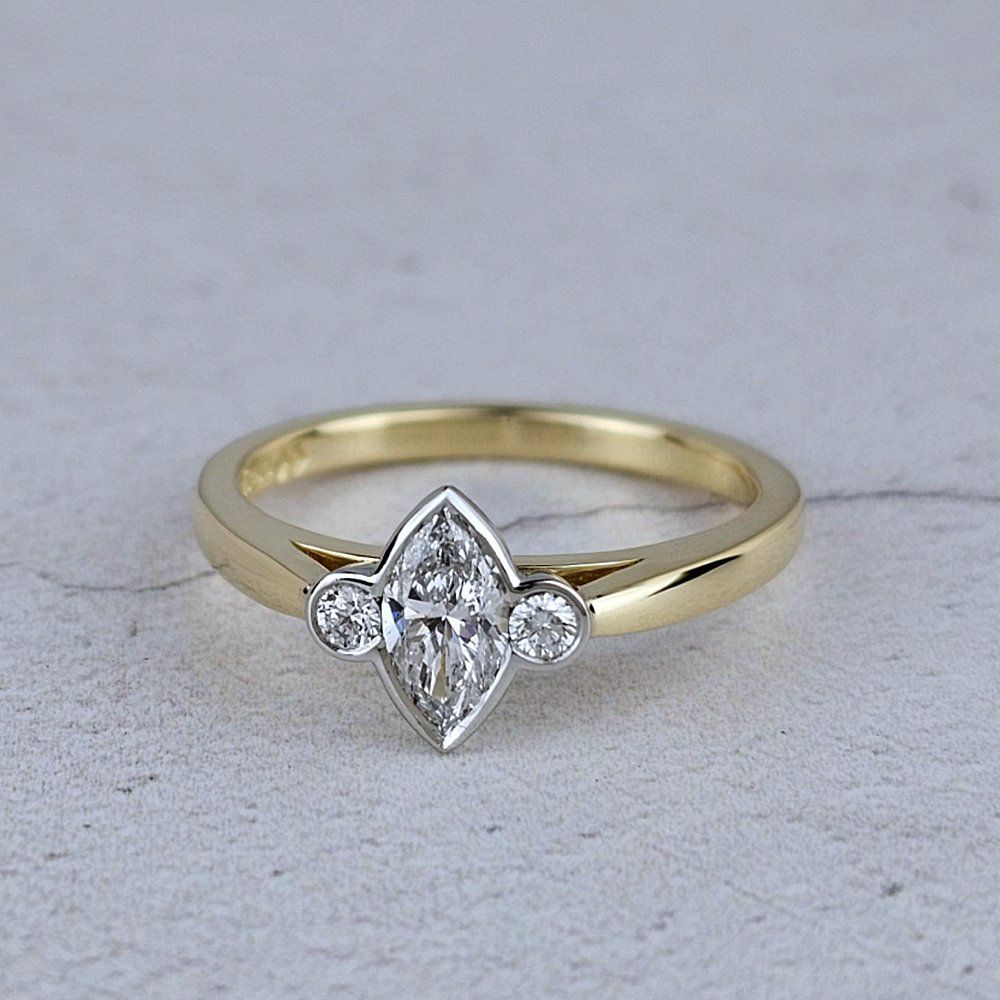 A dainty engagement ring with a marquise and two brilliant-cut diamonds