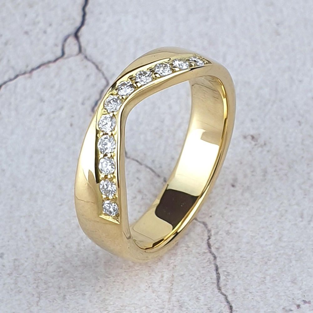 a gold fitted wedding ring shaped on one side and straight  on the other side.