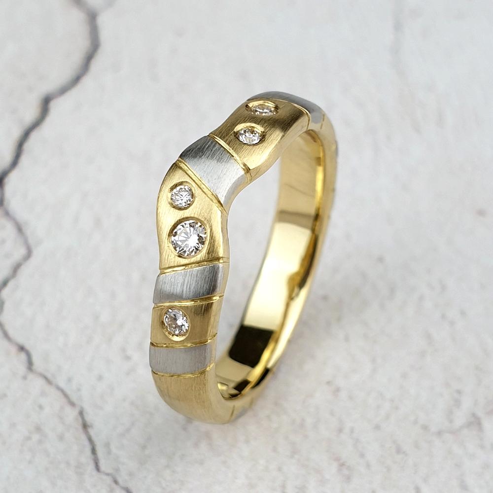 A custom made fitted wedding ring in yellow gold with platinum stripes and diamonds