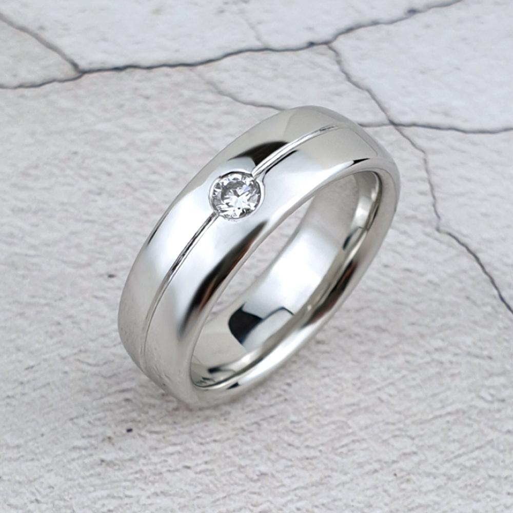 A polished platinum band with a central groove and a single diamond.