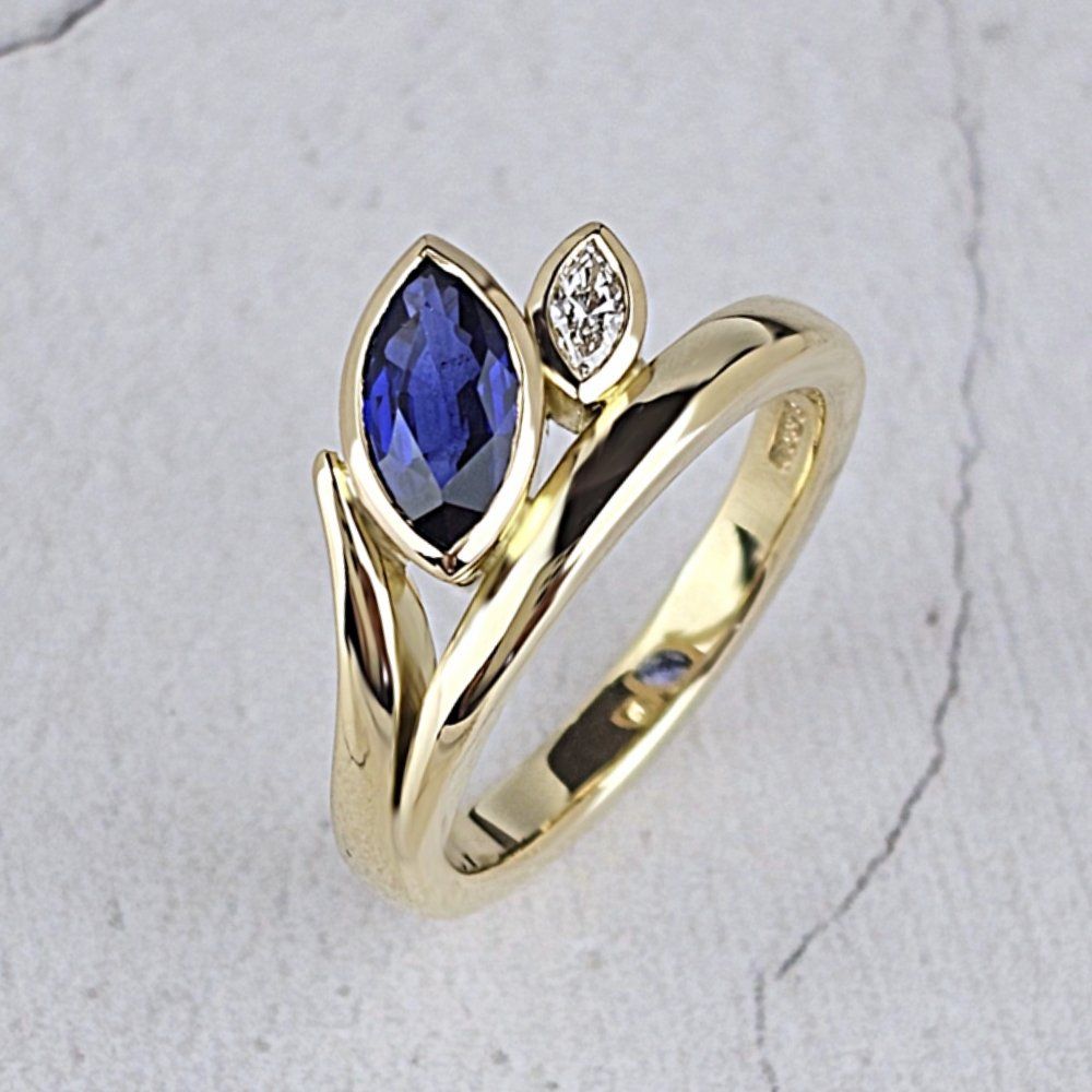 An 18ct yellow gold Flick ring with two marquise stones. Larger blue sapphire and smaller diamond