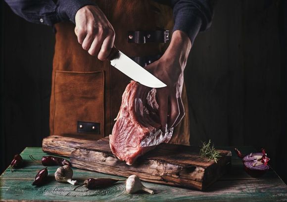 butchers cutting read meat from knife