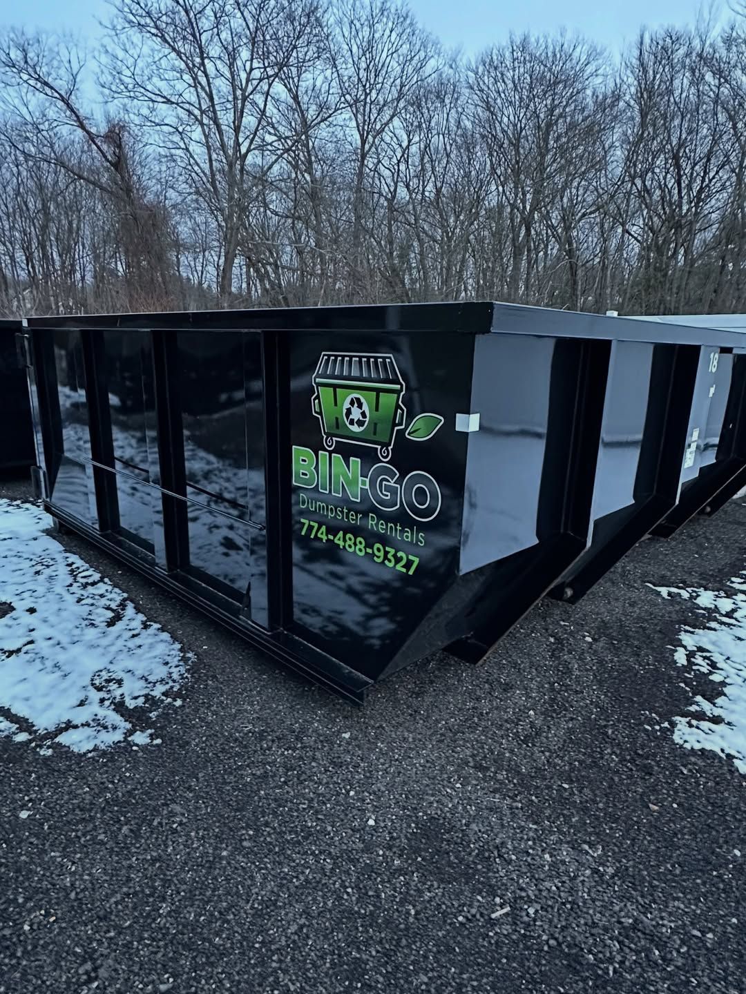 A black dumpster labeled 
