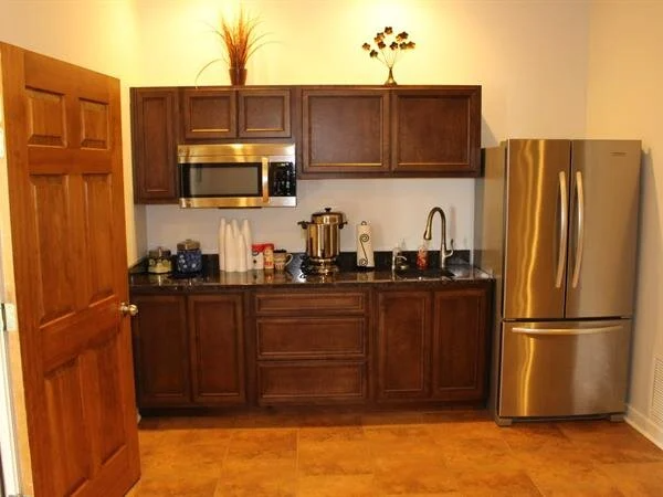 Small kitchen area with brown cabinets, stainless steel appliances, and a granite countertop.