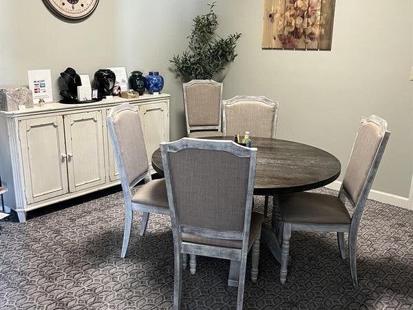 A dining room with a round table and five chairs. A sideboard with decor sits against the wall.