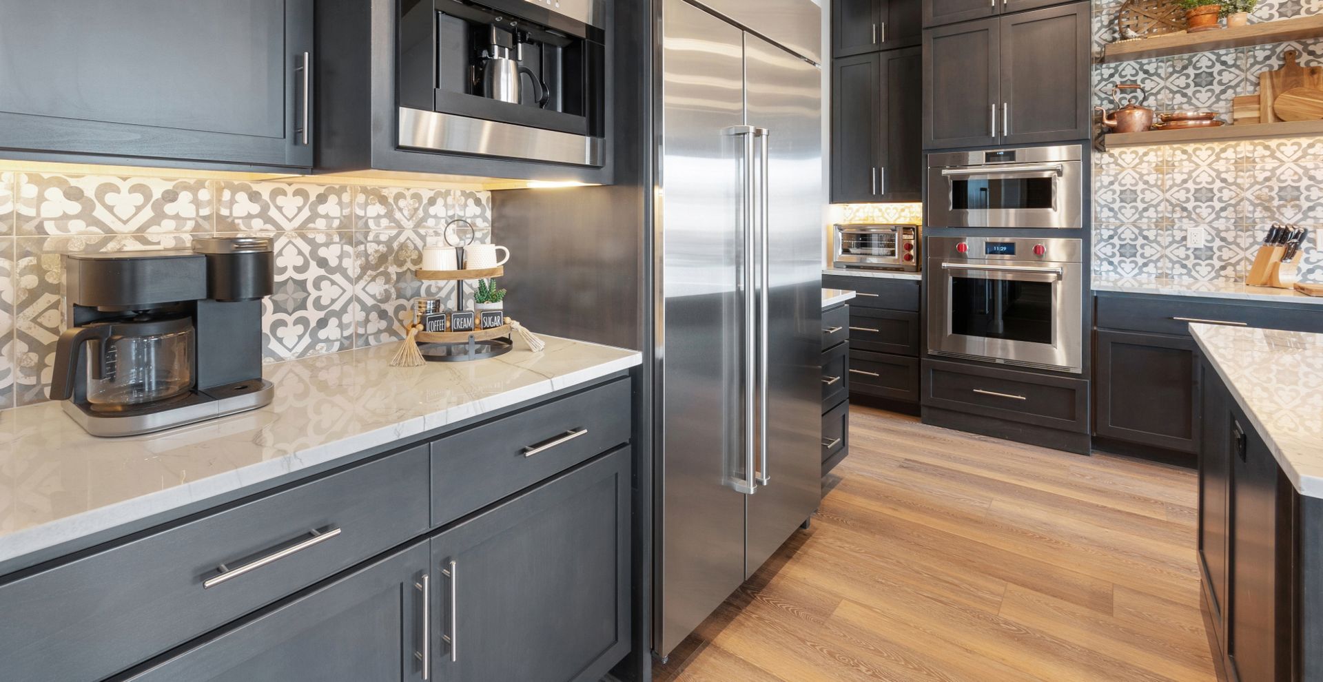 Modern kitchen with dark gray cabinets, stainless steel appliances, and patterned backsplash.