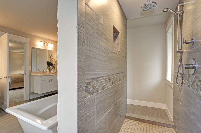 Bathroom with large tiled shower, bathtub, and vanity with white cabinets.