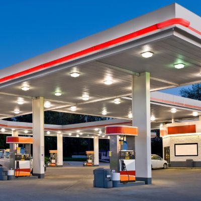 Gas station canopy with orange and white pumps and a small convenience store.