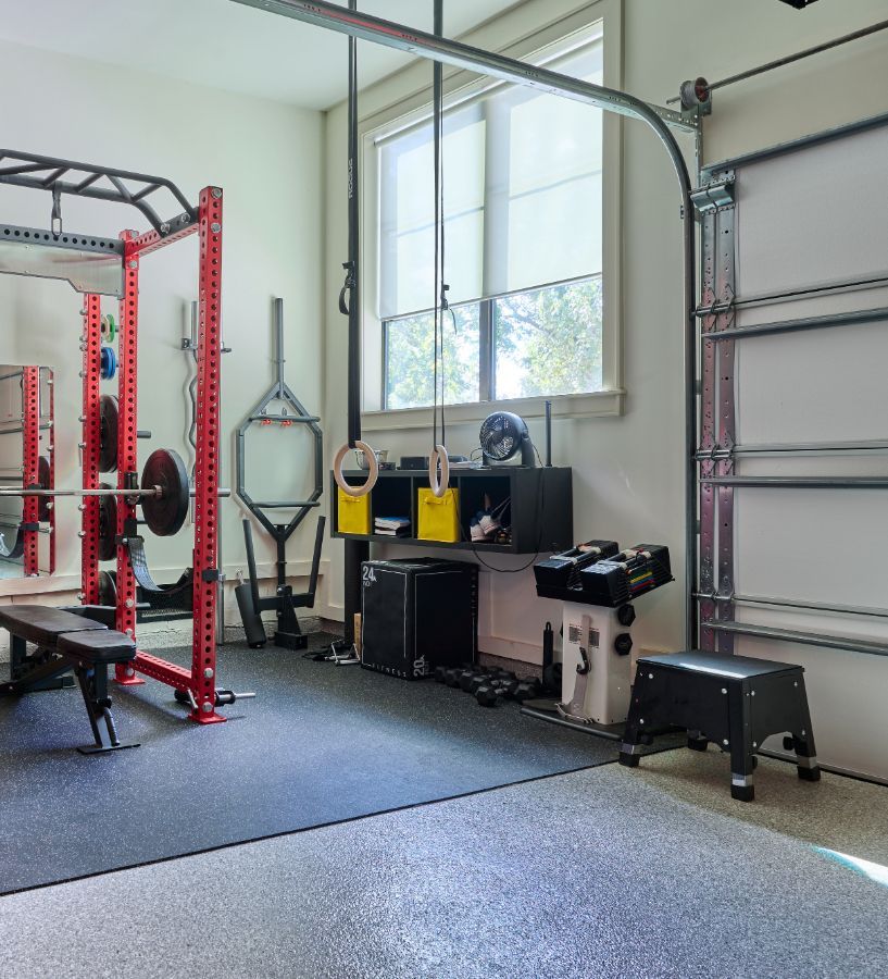 Home gym with red squat rack, weight bench, and various exercise equipment.