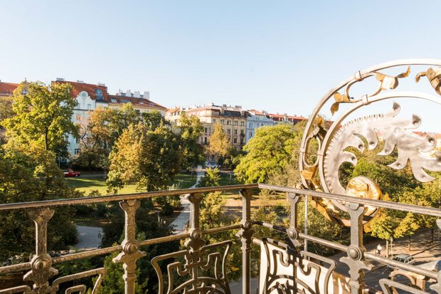 View from a decorated balcony overlooking a park and city buildings on a sunny day.