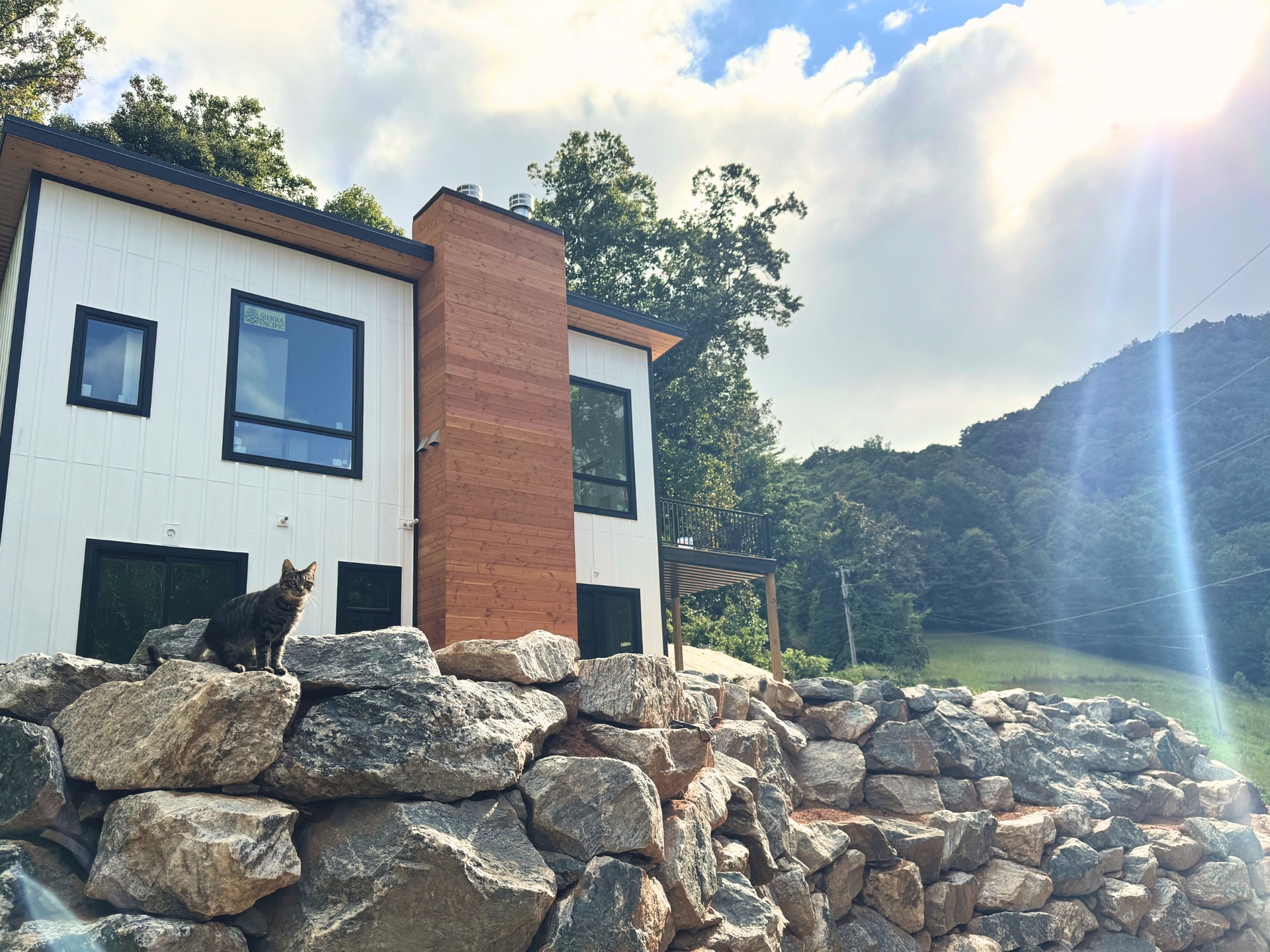 photo of the heirloom healing house while it was under construction with moonface sitting in a sunbeam on the rocks