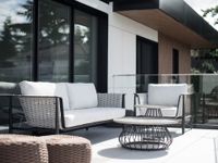 White outdoor patio chairs around a black fire pit on a deck, with a green backyard and trees beyond.