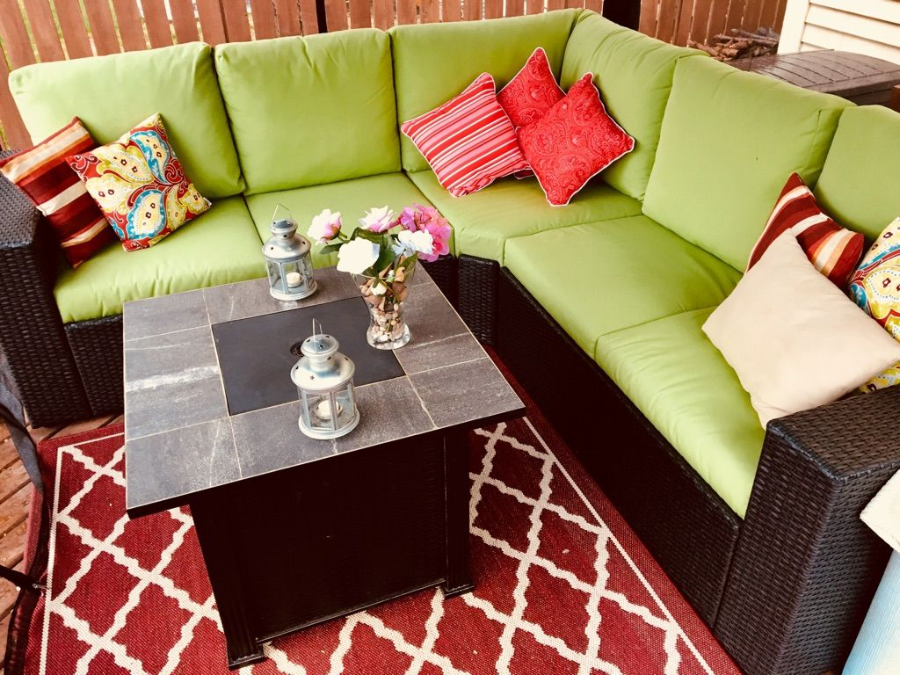 Lime green sectional patio sofa with colorful pillows around a dark coffee table on a red patterned rug