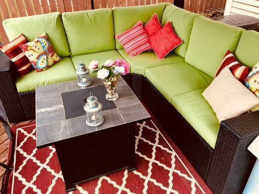 Lime-green sectional sofa with colorful pillows around a black coffee table on a red patterned rug