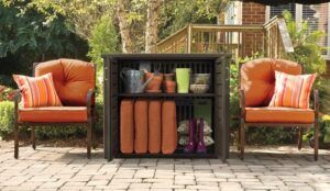 Outdoor patio with two orange armchairs and a black storage cabinet holding cushions and decor