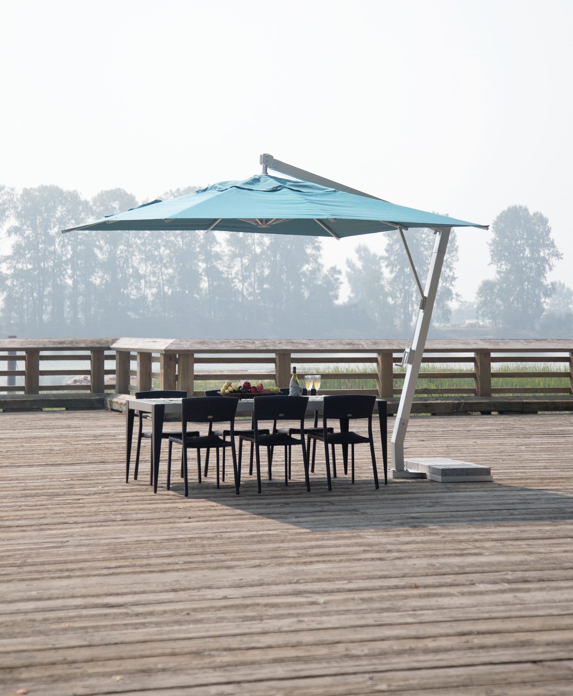 Patio deck with black wicker seating, red cushions, fire pit table, and large umbrella