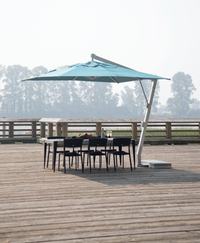 Patio deck with black wicker seating, red cushions, fire pit table, and large umbrella