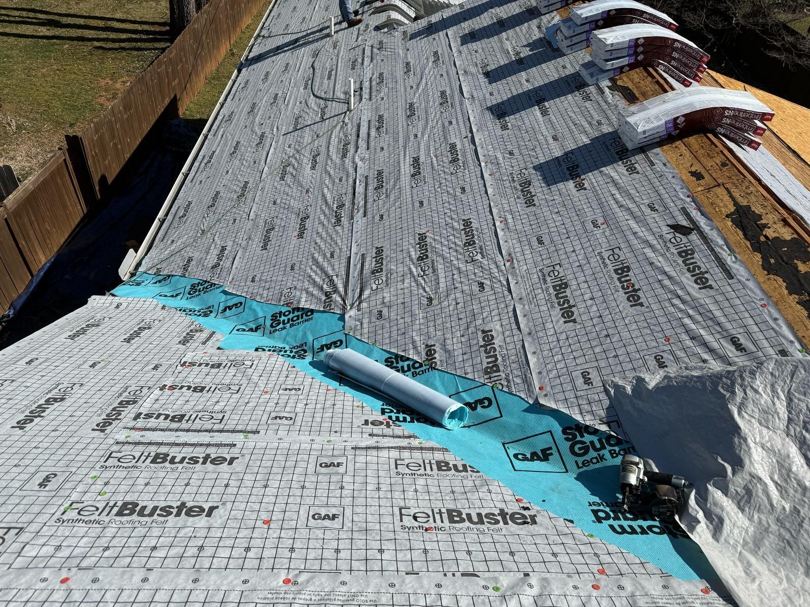 Roof with underlayment installed, preparing for shingle application; rolls of shingles are visible.
