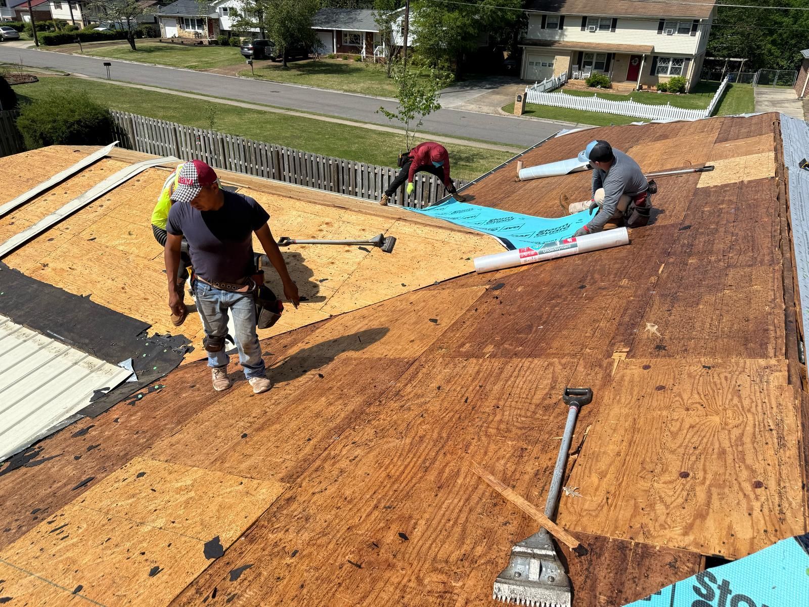 Roofers installing roofing material on a house, sunny day.