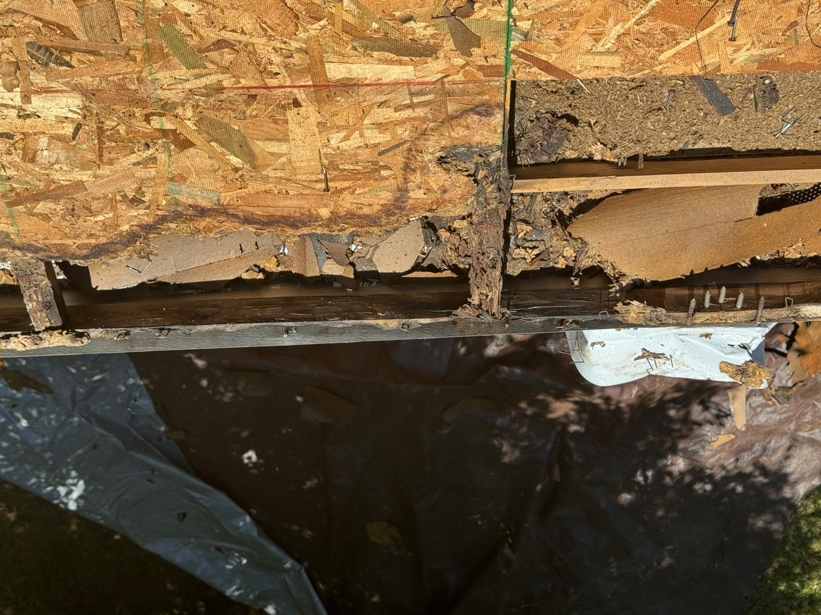 Damaged roof edge with exposed wood, dark underlayment, and deteriorated materials.