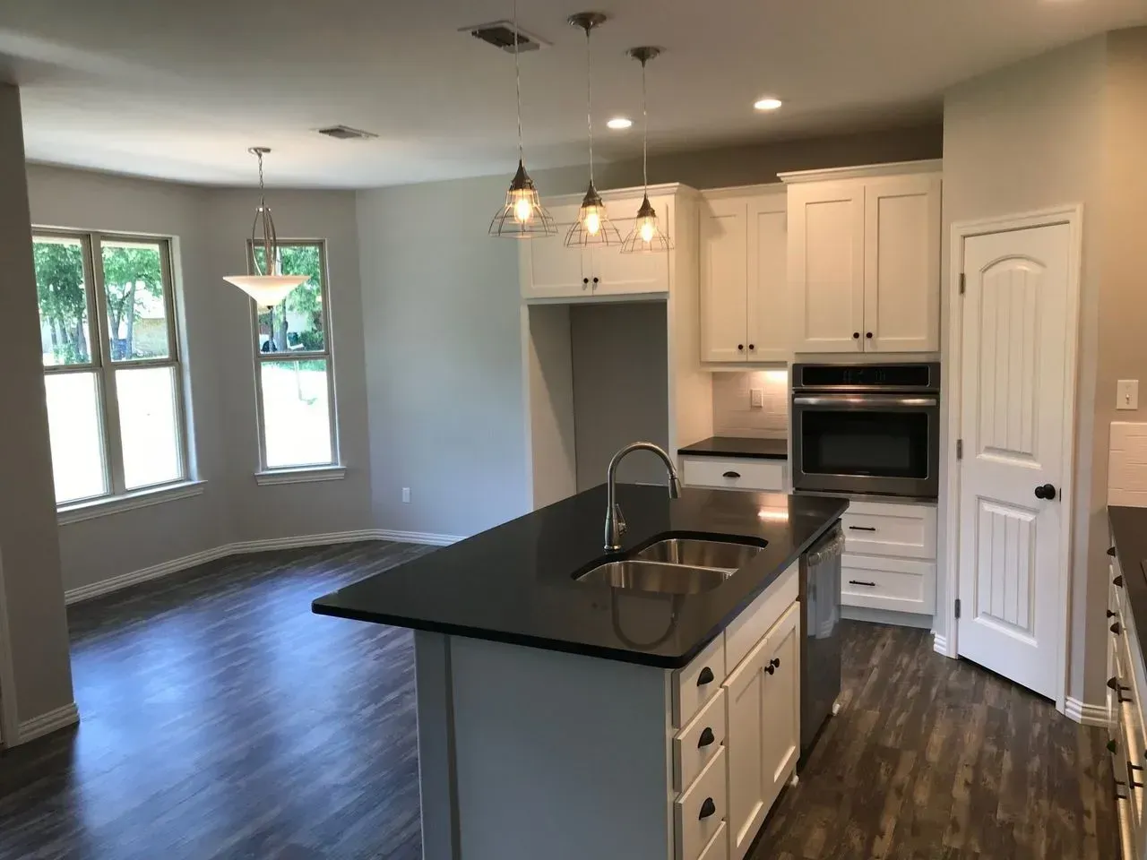 A kitchen with white cabinets and black counter tops