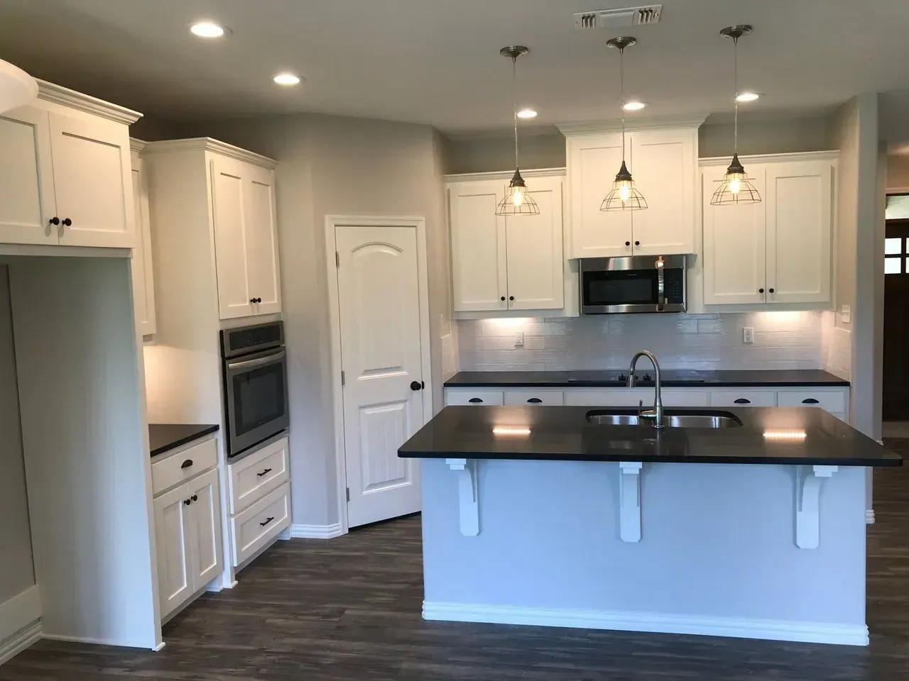 A kitchen with white cabinets and black counter tops
