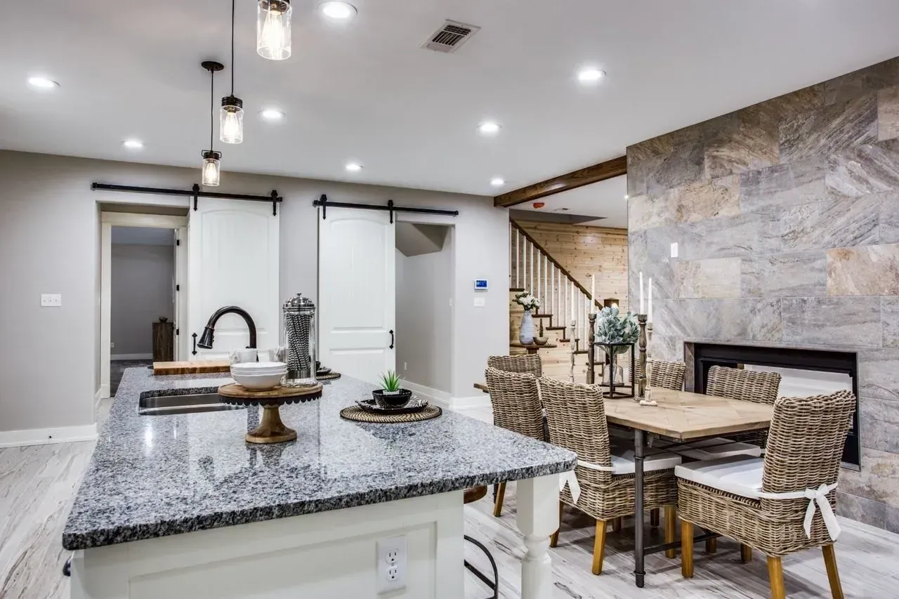 A kitchen with a large island and a dining table and chairs.