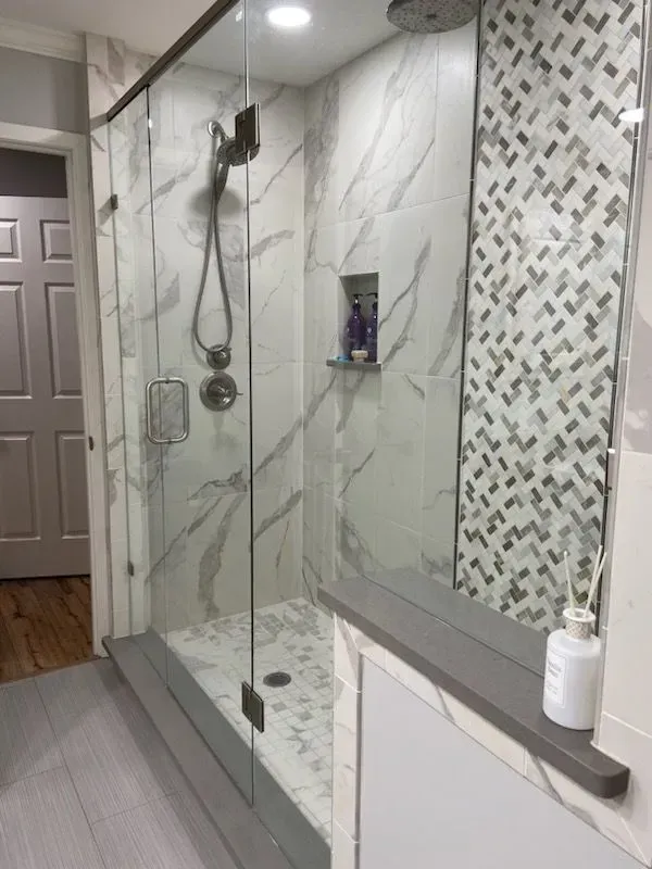 A bathroom with a walk in shower and a mirror.