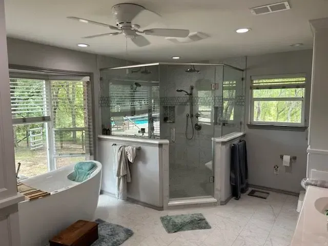 A bathroom with a tub , shower , and ceiling fan.