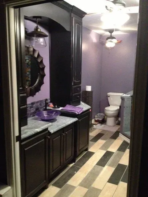 A bathroom with purple walls and black cabinets