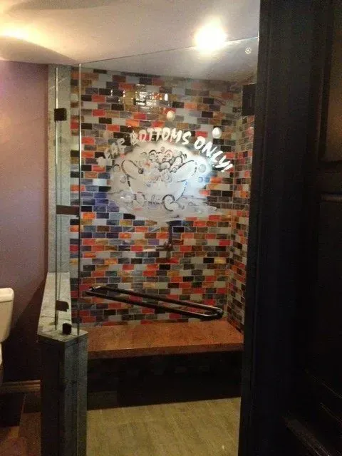 A bathroom with a brick wall and a sign that says bottoms only