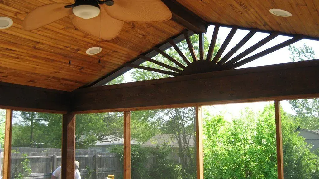 A screened in porch with a ceiling fan and lots of windows