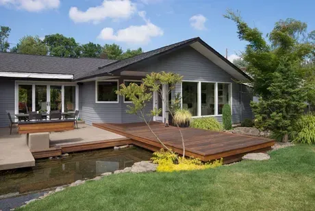 A house with a deck and a pond in front of it