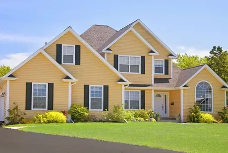 A large yellow house with black shutters on the windows