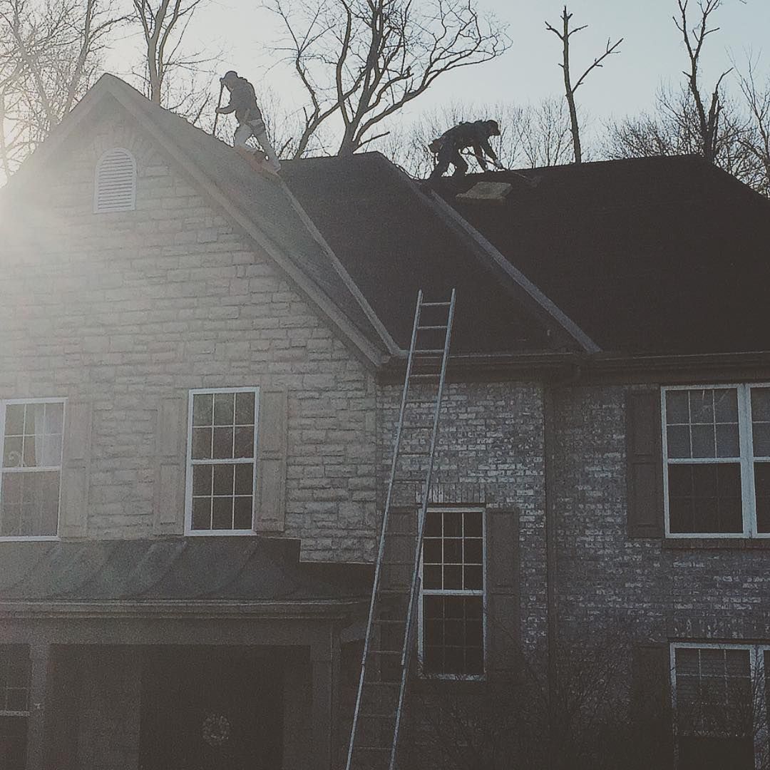 Two men are working on the roof of a house.