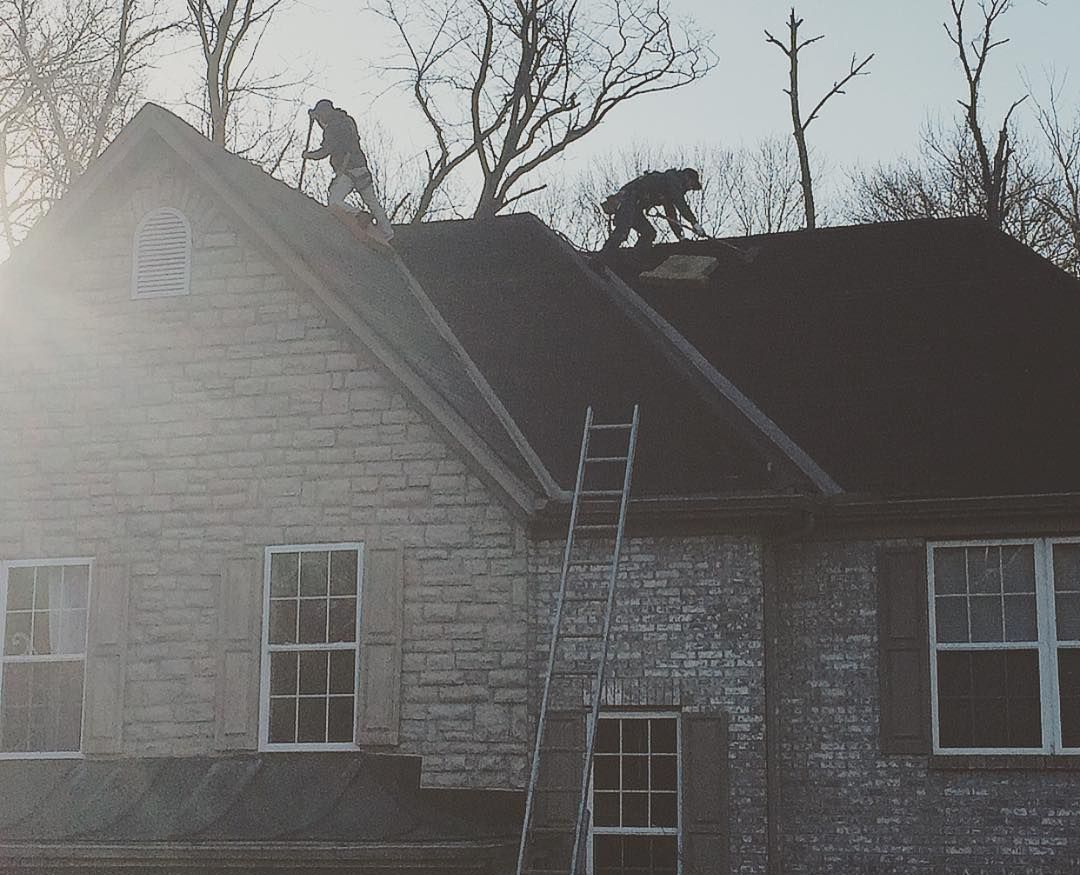 Two men are working on the roof of a house.