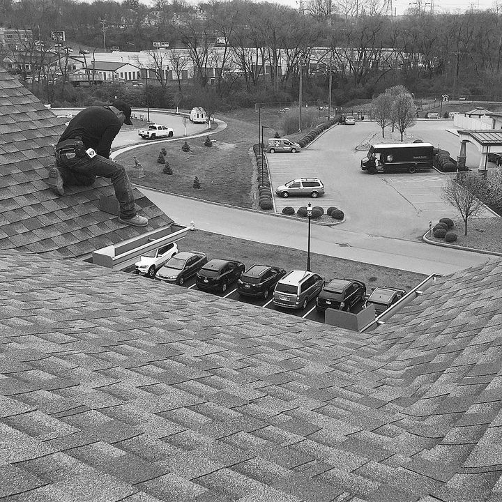 A black and white photo of a man sitting on top of a roof.