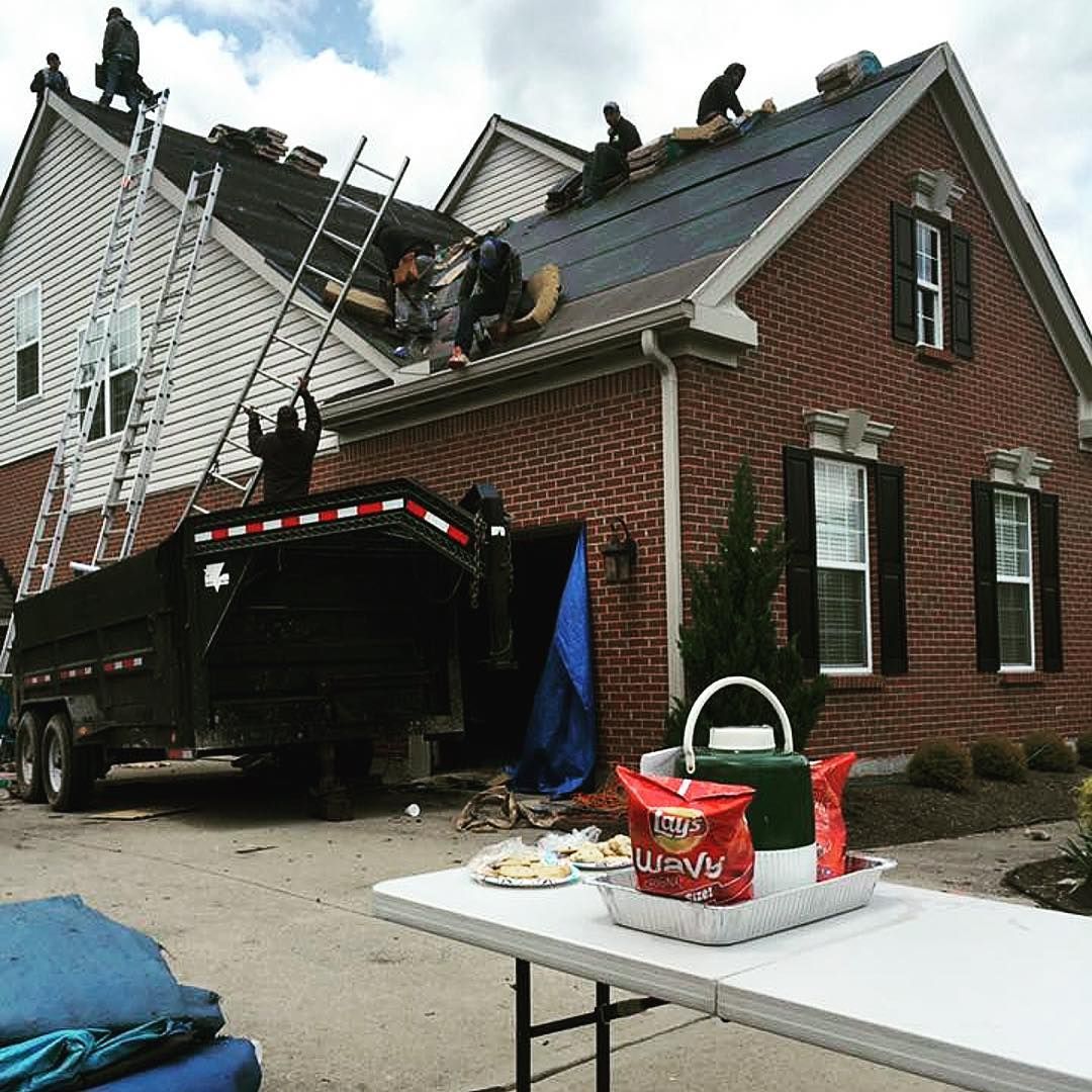 A group of people are working on the roof of a house.
