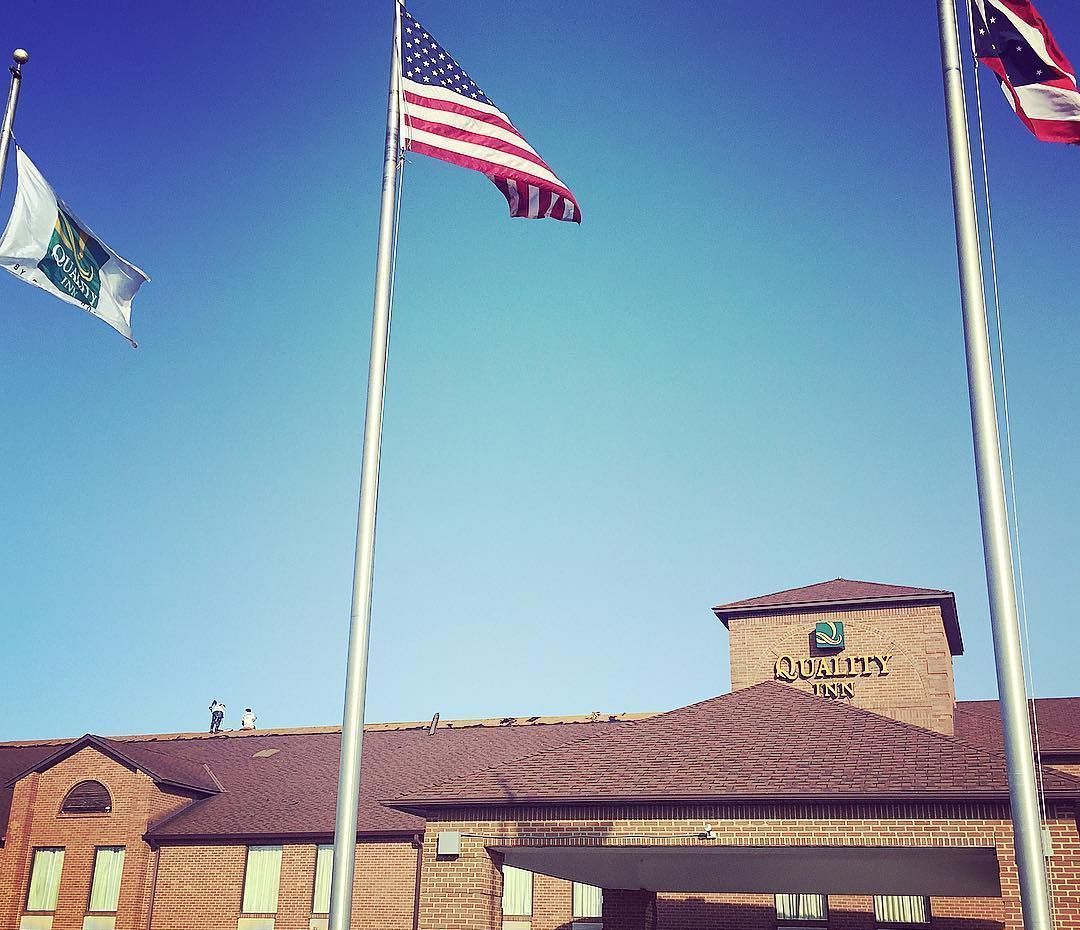 Three flags are flying in front of a brick building