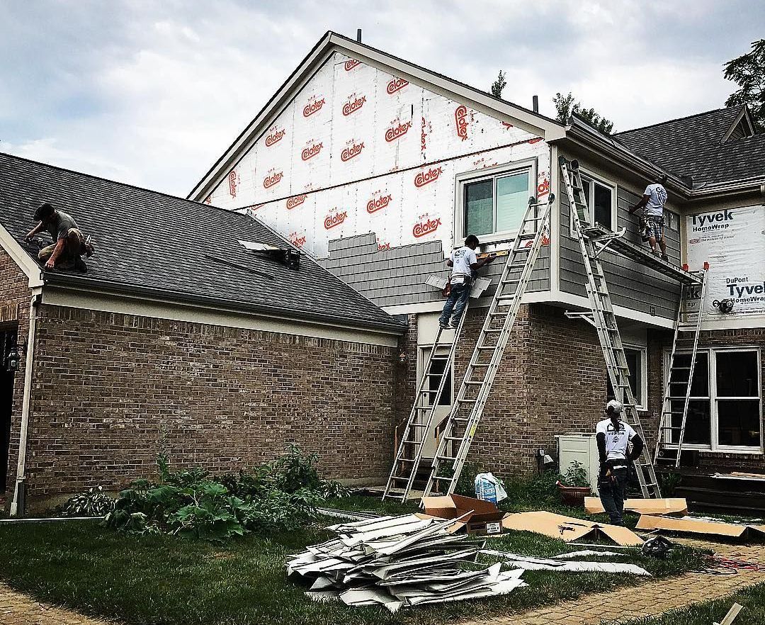 A group of people are working on the roof of a house.