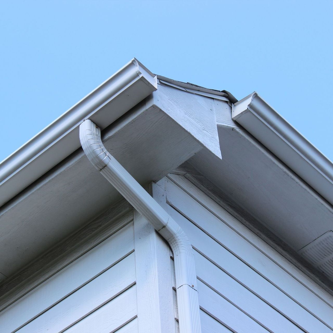 A white house with a gutter on the side of it